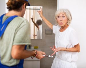 Stressed elderly woman talking with plumber