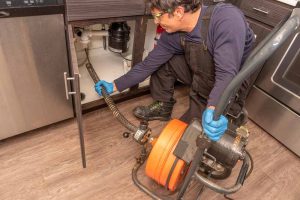 plumber using an auger maching to snake a drain Kirkland, WA