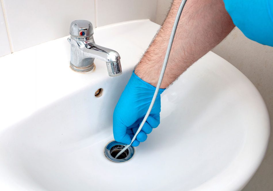 plumber repairing drain with plumbers snake