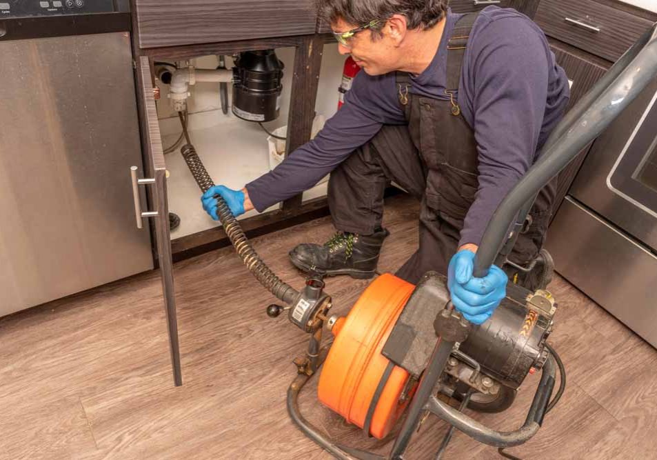 plumber using an auger maching to snake a drain Kirkland, WA